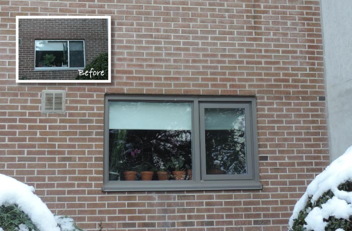 New grey-framed window set in repaired brick masonry with snow on the shrubs below; inset shows the old window before replacement