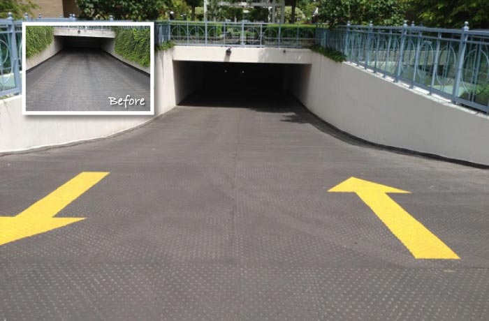 Resurfaced parking garage entrance ramp with fresh yellow directional arrows; inset shows the ramp before resurfacing
